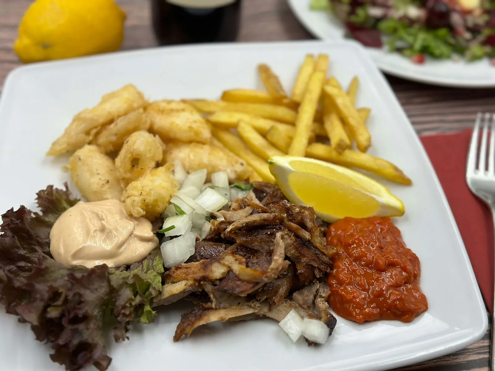Tallerken med gyroskjøtt, pommes frites, sitron og sauser